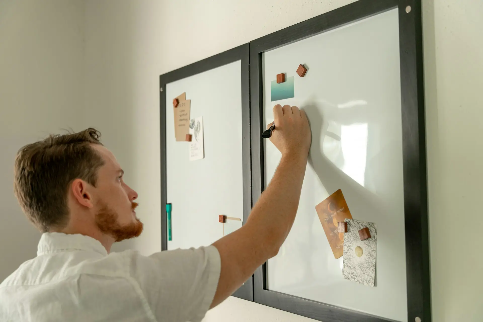 a man writing on a white board with sticky notes on it